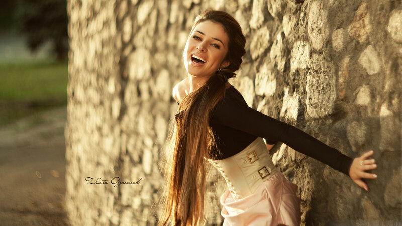 Woman Leaning on Stone Wall — Brown, Dramatic, Sunset