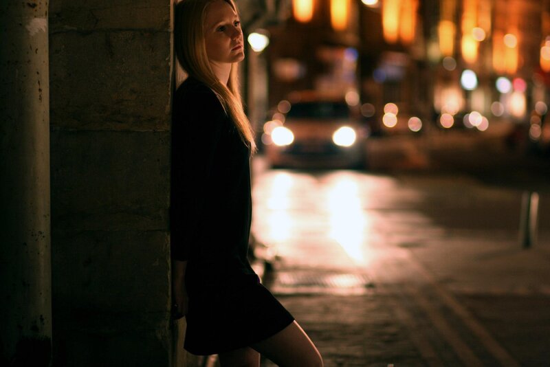woman leaning on wall at night