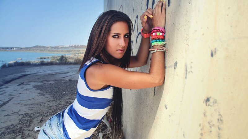 woman leaning on wall by water