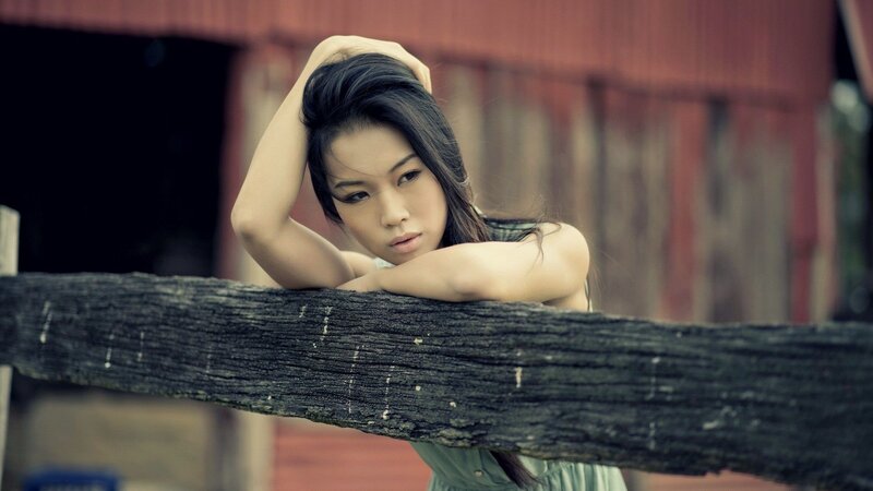 woman leaning on wooden fence