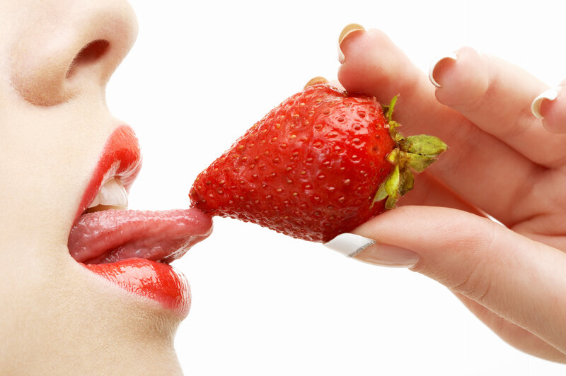 woman licking a strawberry