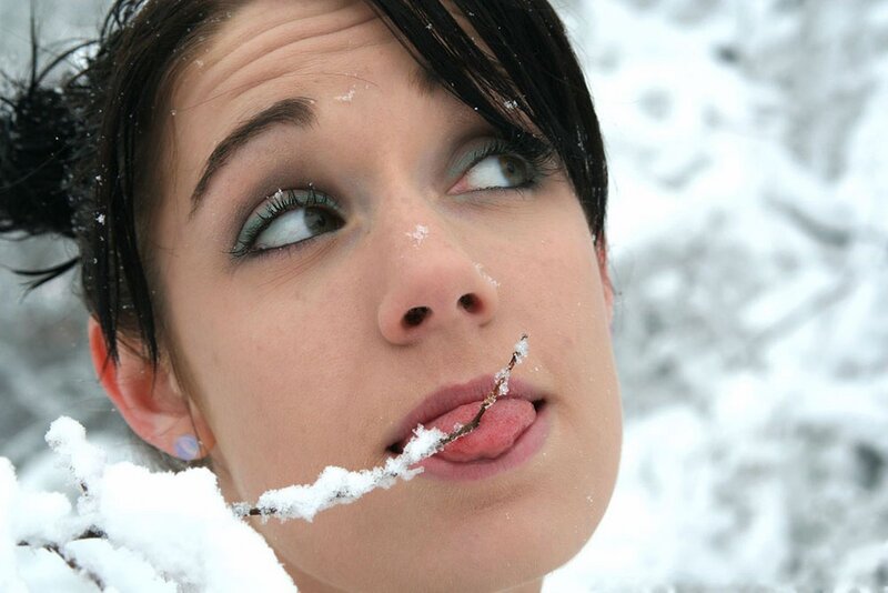 woman licking snow-covered branch