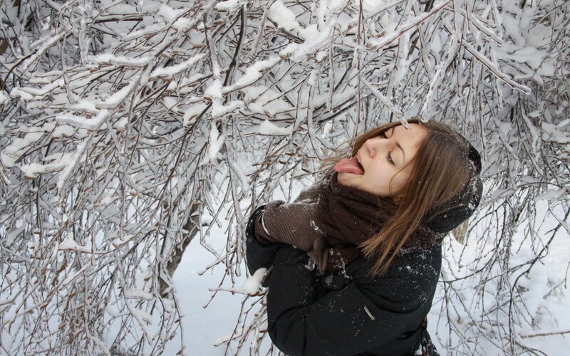 woman licking snow-covered branch