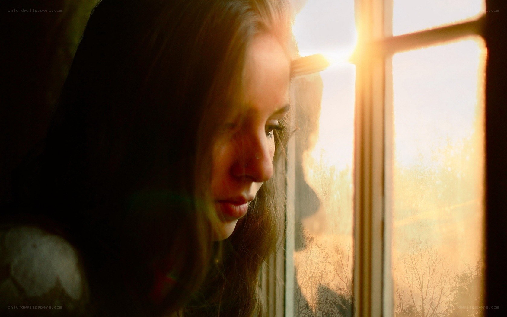 woman looking out window at sunset