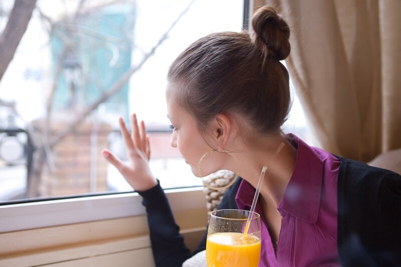 woman looking out window with juice