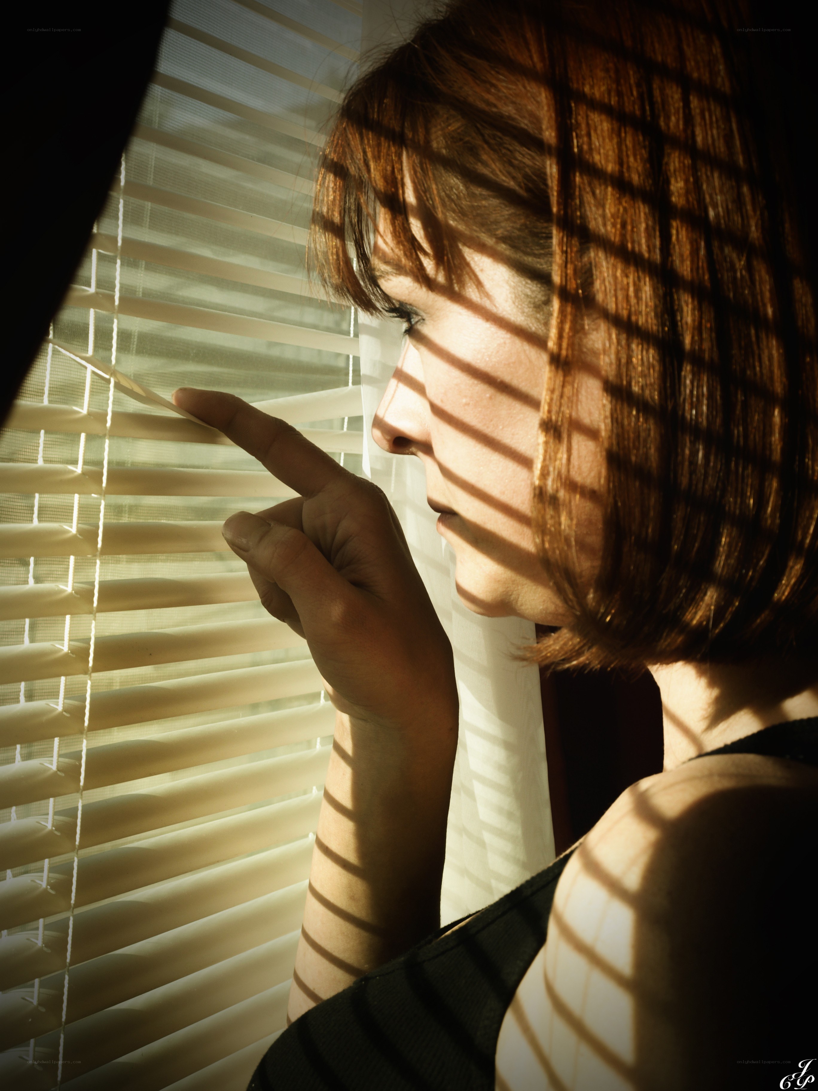 woman looking through blinds