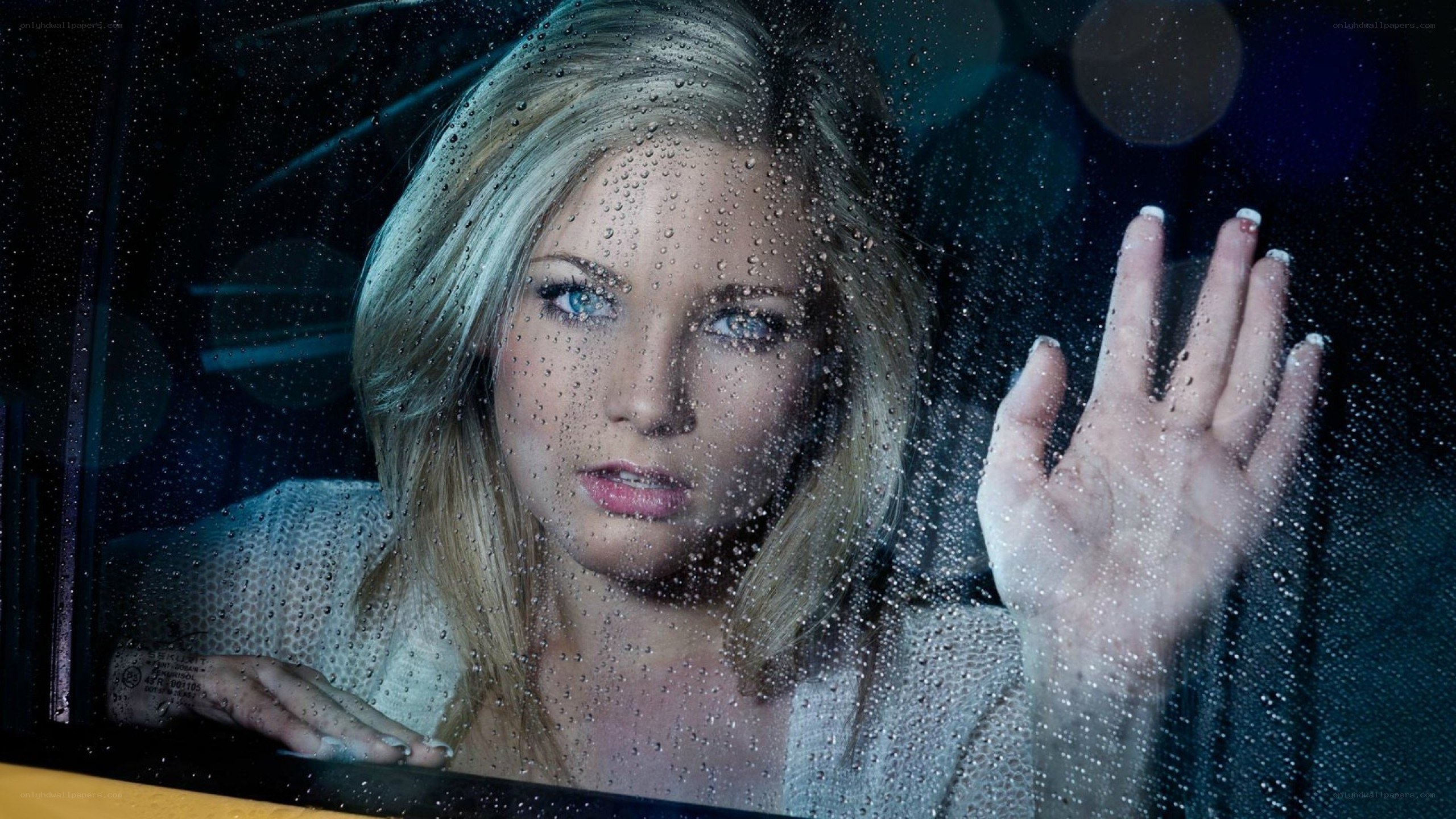 woman looking through rain-covered window