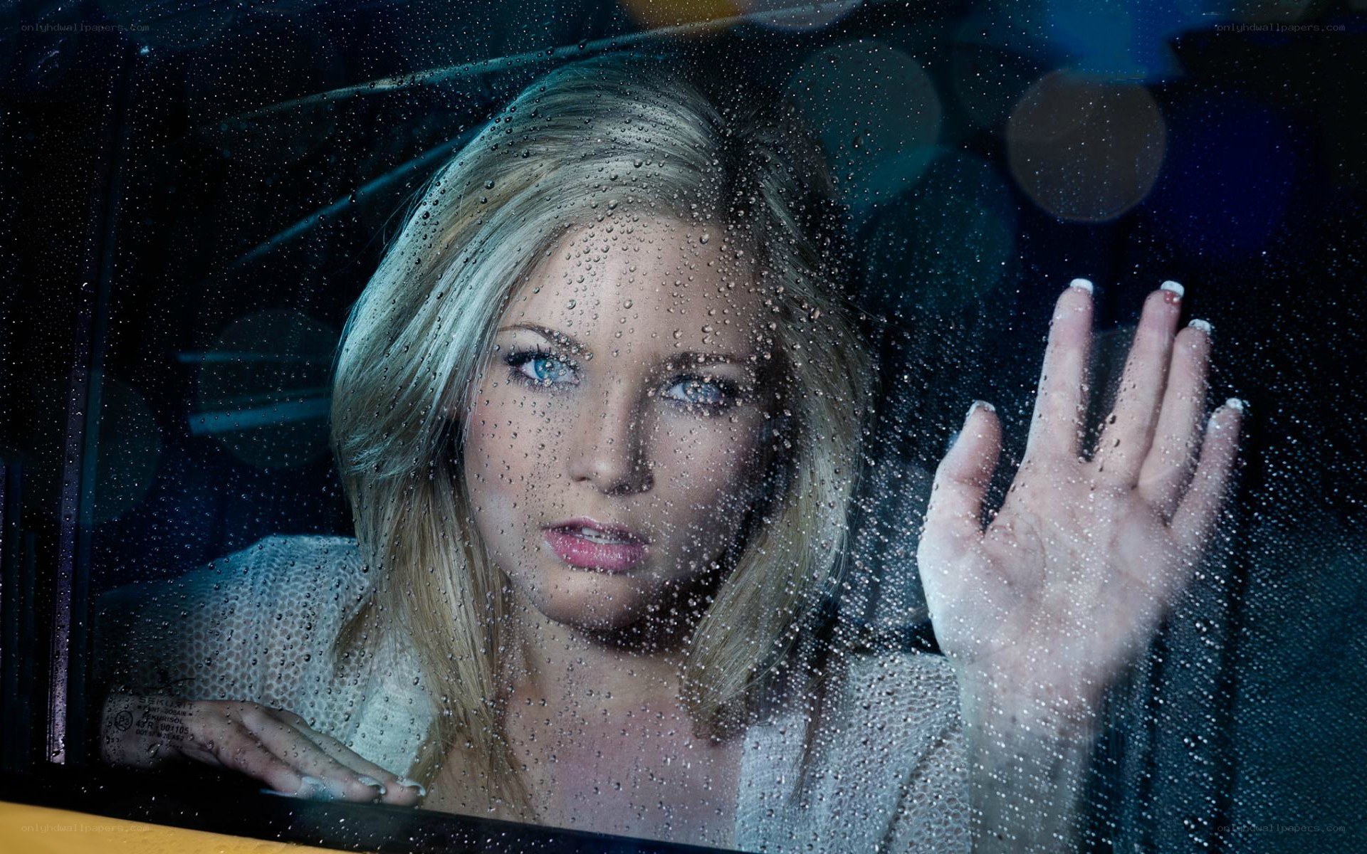 woman looking through rain-covered window