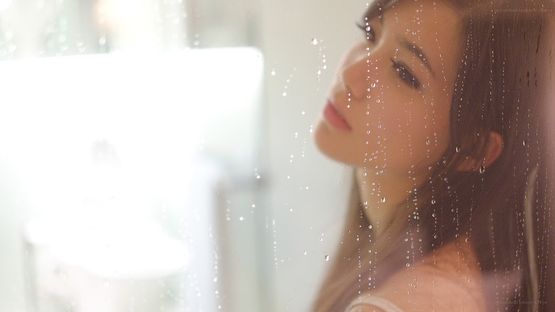 woman looking through rain-streaked window