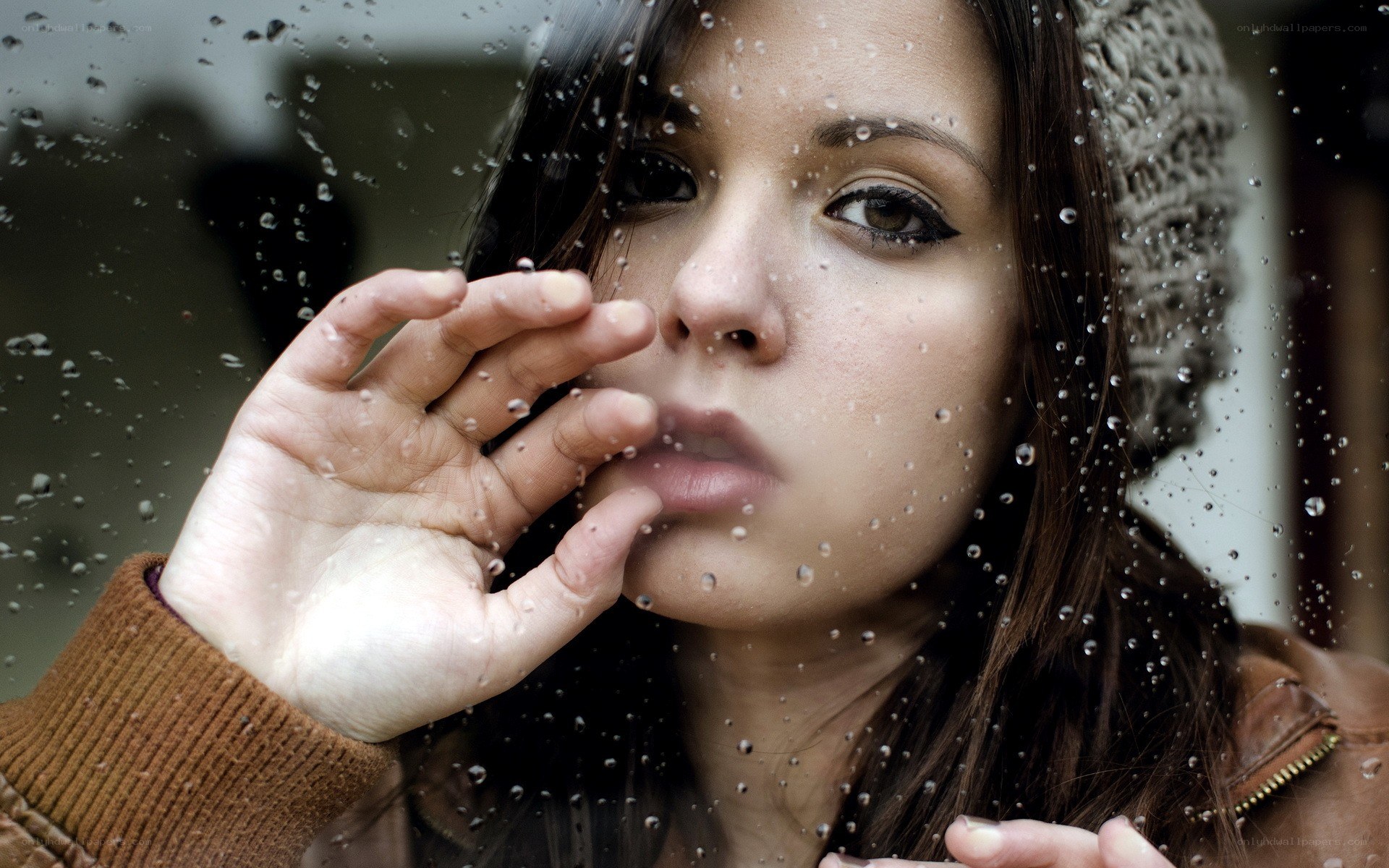 woman looking through rain-streaked window