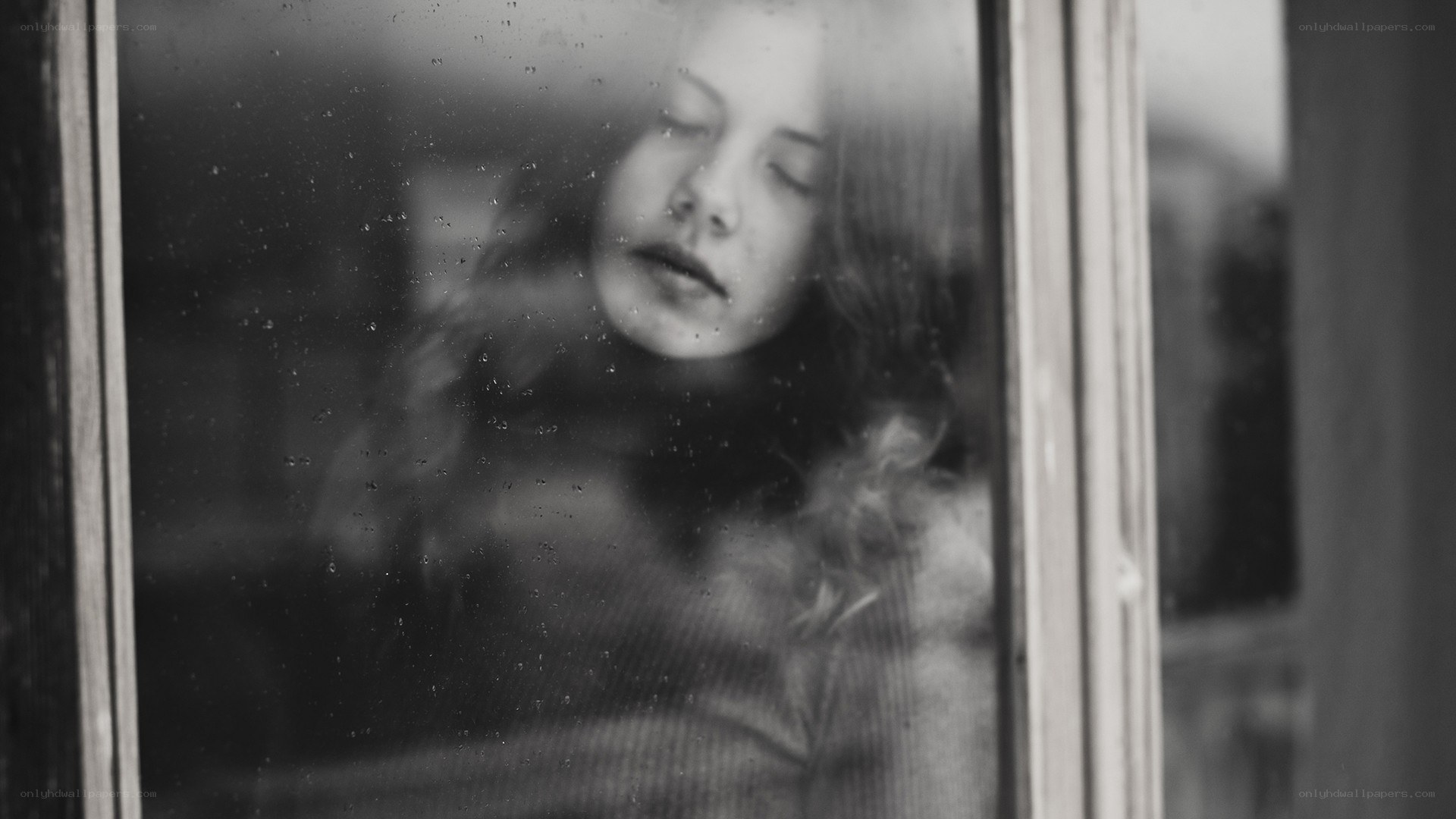 woman looking through rain-streaked window