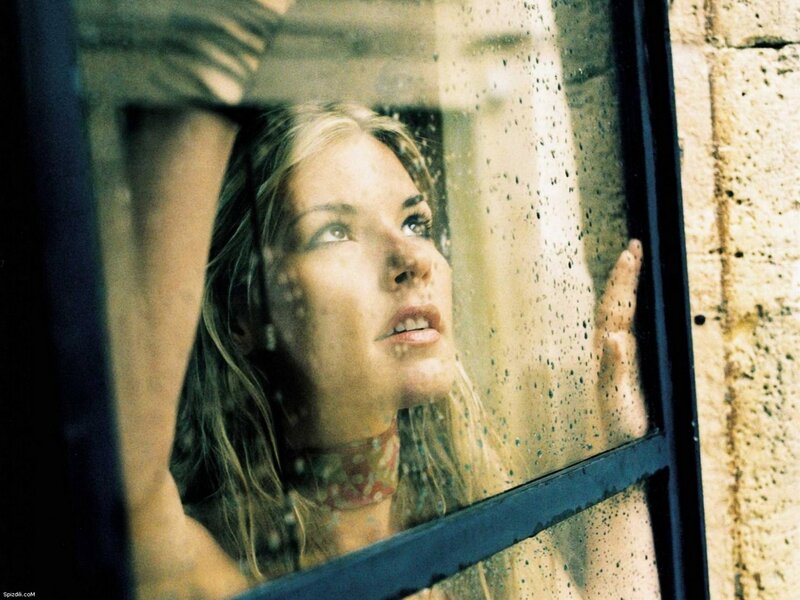 woman looking through rain-streaked window