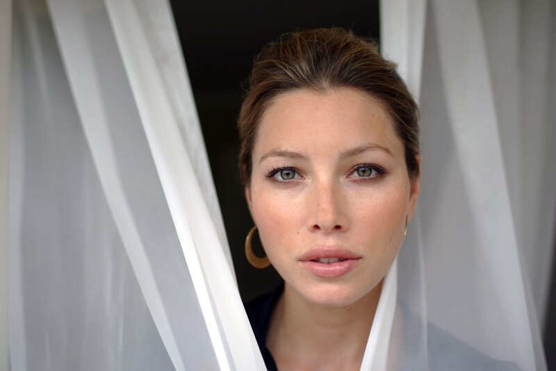 woman looking through sheer curtains