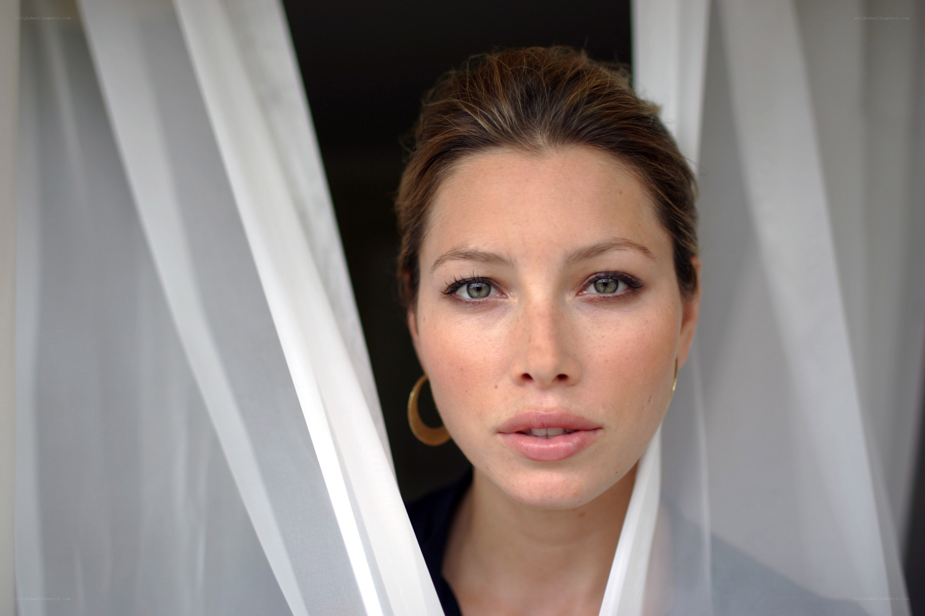 woman looking through sheer curtains