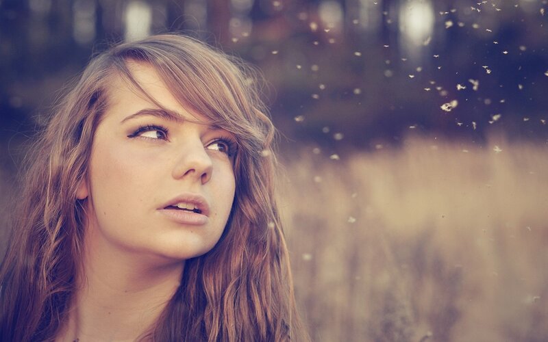 woman looking up at dandelion seeds