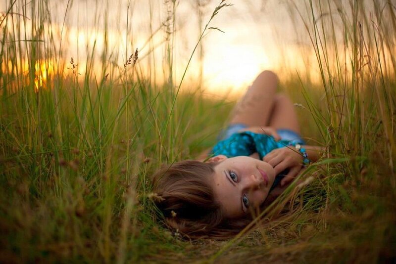 woman lying in a field at sunset