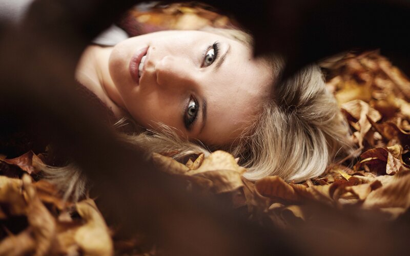 woman lying in autumn leaves