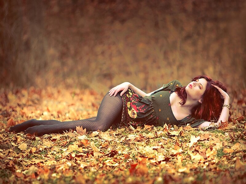 Woman lying in autumn leaves
