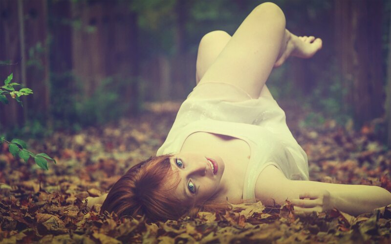 woman lying in autumn leaves