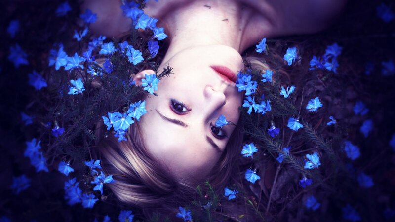 woman lying in blue flowers