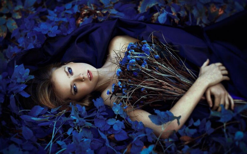 Woman Lying in Blue Leaves — Dramatic, Photograph
