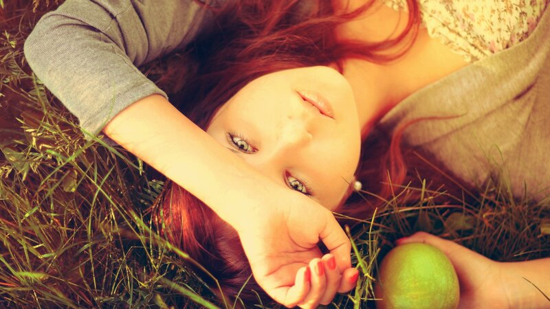 woman lying in grass with apple