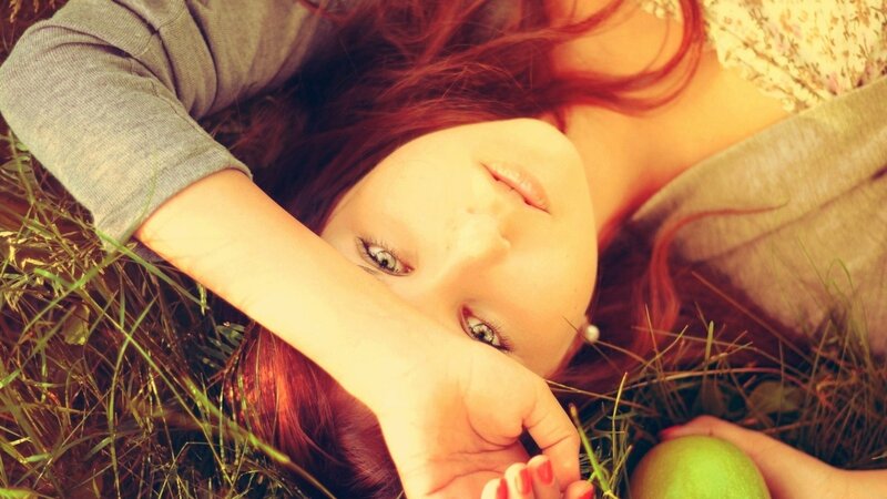 woman lying in grass with apple