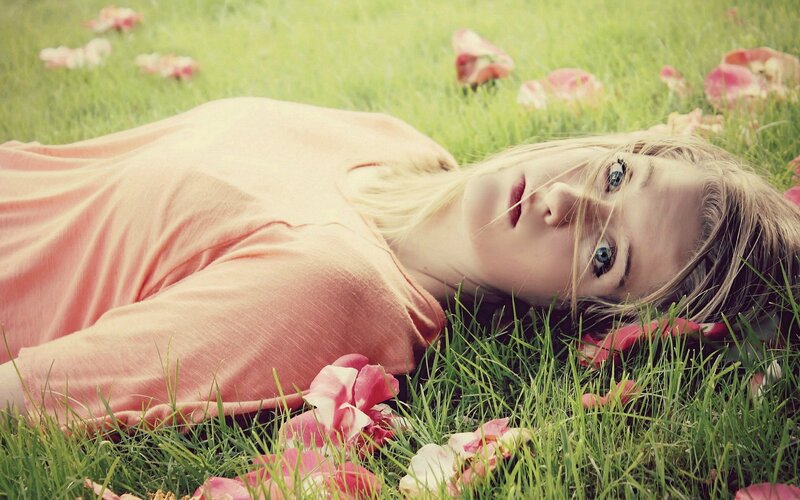 woman lying in grass with petals