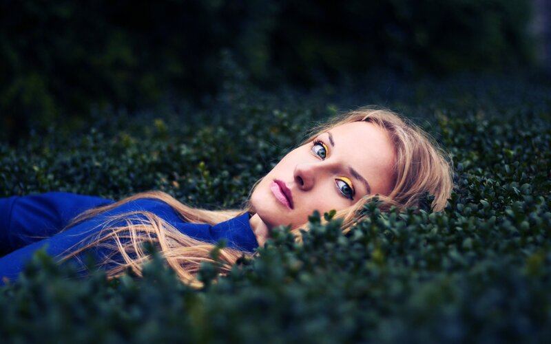 woman lying in green bushes