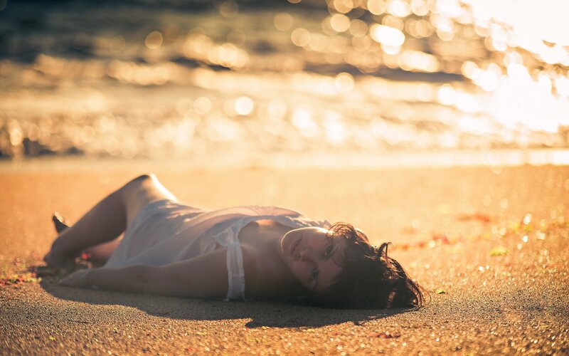 woman lying on beach at sunset