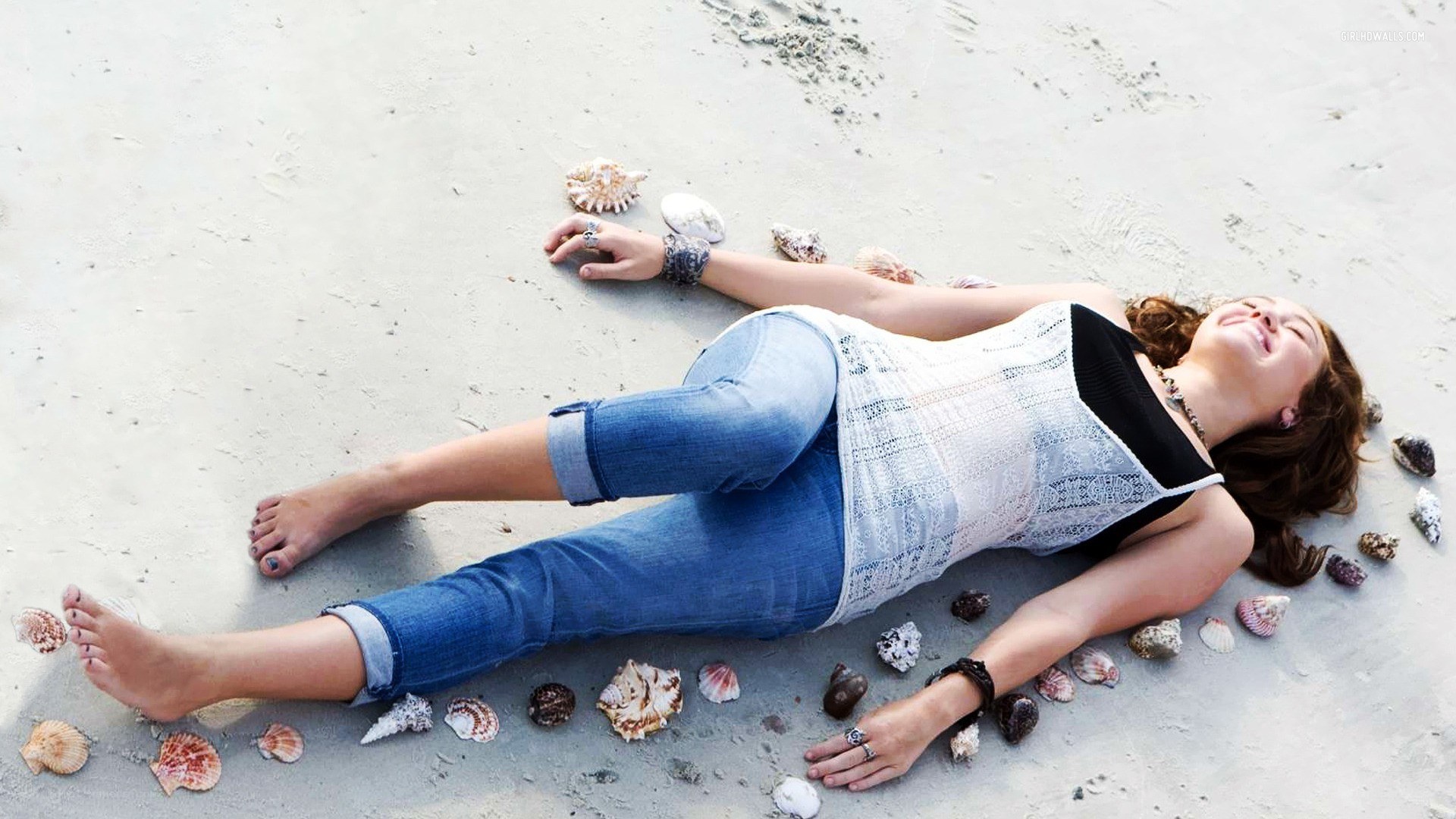 Woman lying on beach with seashells