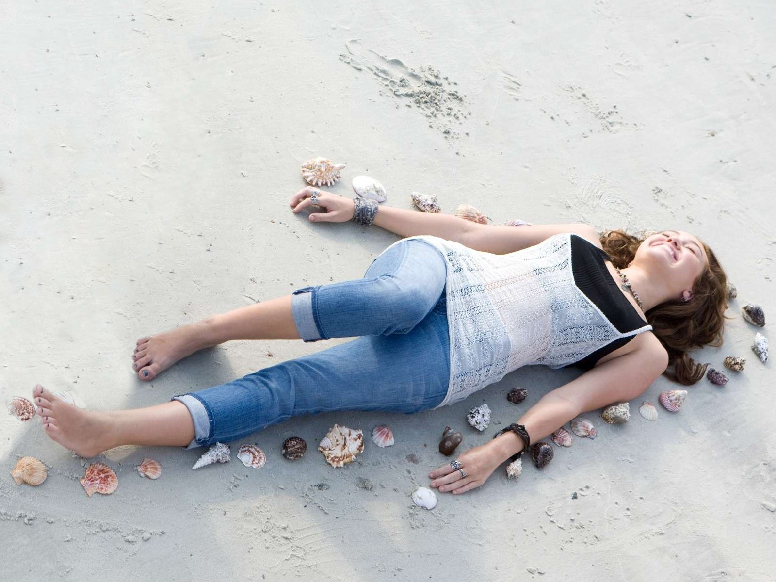 Woman lying on beach with seashells