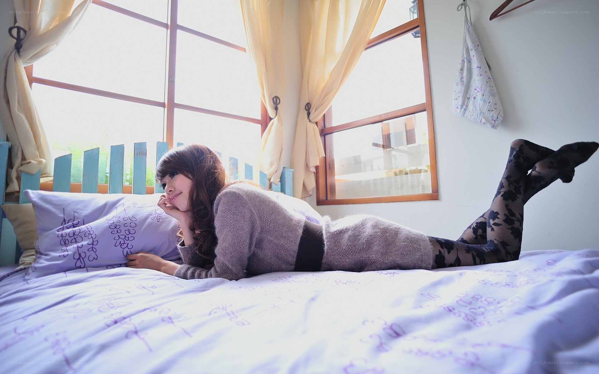 woman lying on bed by window