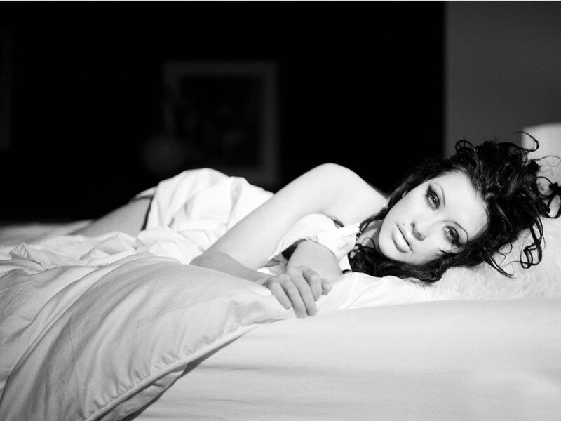 woman lying on bed in black and white