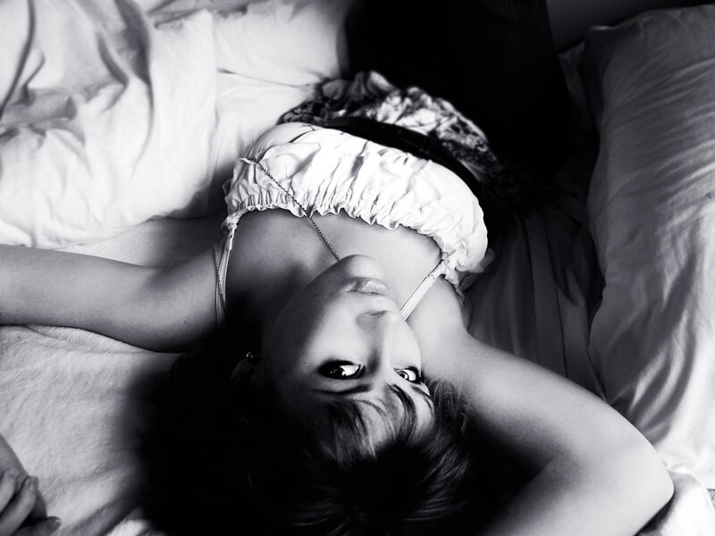 woman lying on bed in black and white