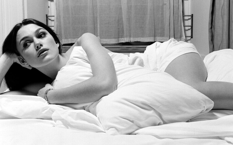 woman lying on bed in black and white