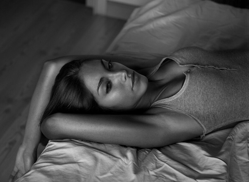 woman lying on bed in black and white