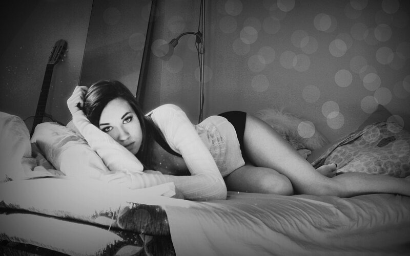 woman lying on bed in black and white