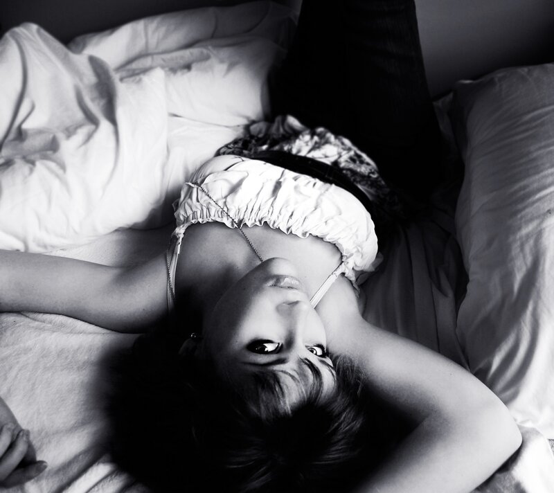 woman lying on bed in black and white