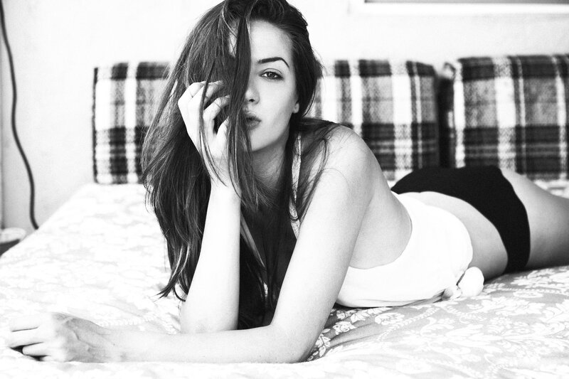 woman lying on bed in black and white
