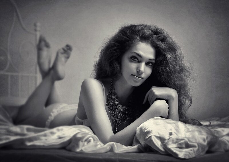 woman lying on bed in black and white