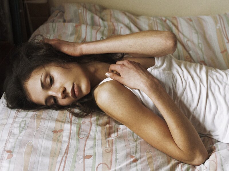 woman lying on bed in white shirt