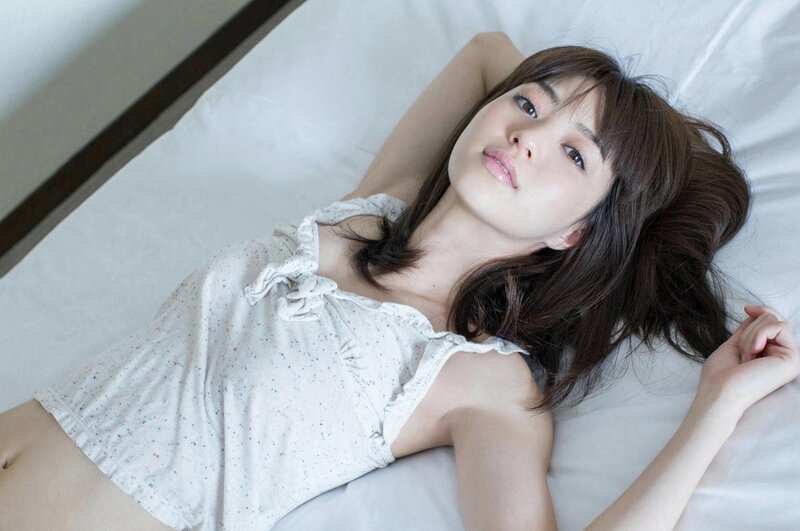 woman lying on bed in white top