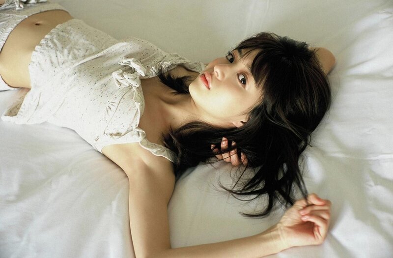 woman lying on bed in white top
