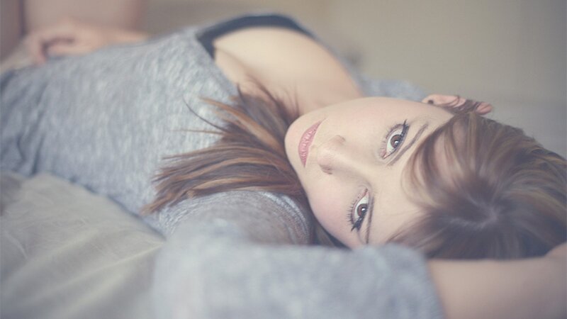 woman lying on bed looking at camera