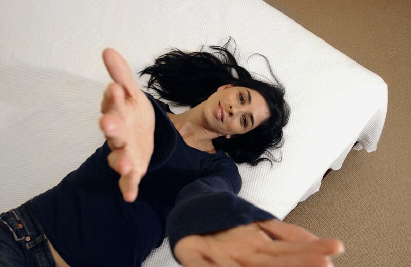 woman lying on bed reaching out