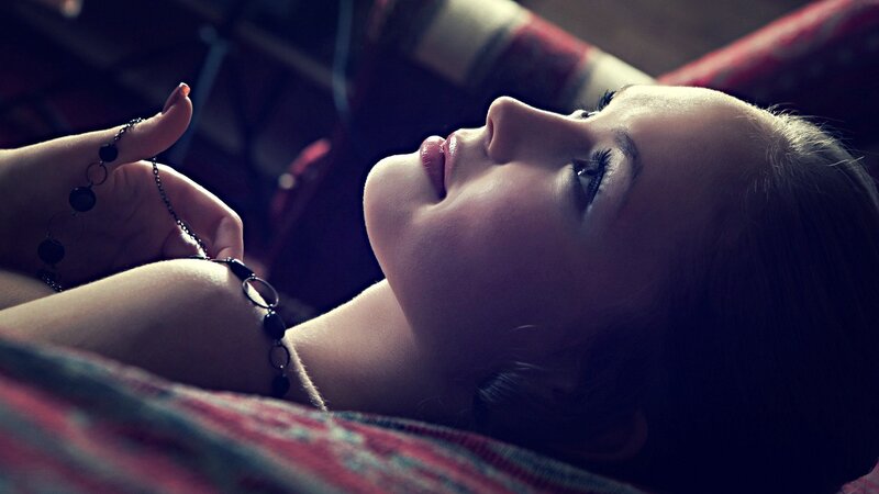 woman lying on bed with necklace