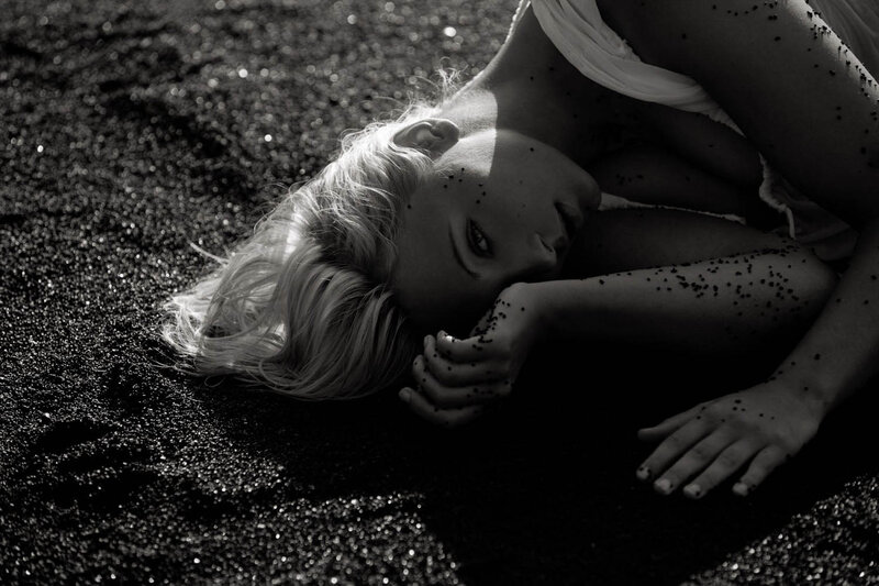 Woman Lying on Black Sand — Dramatic