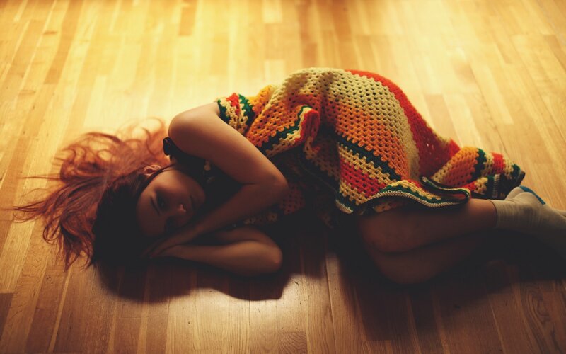 woman lying on floor with blanket