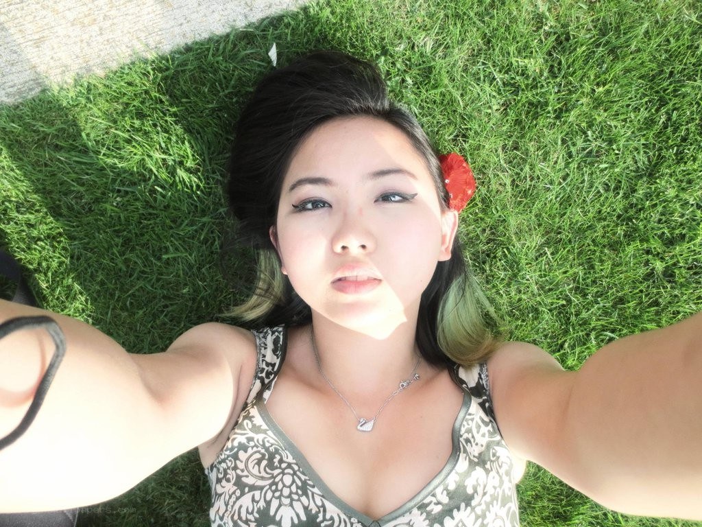 woman lying on grass taking selfie